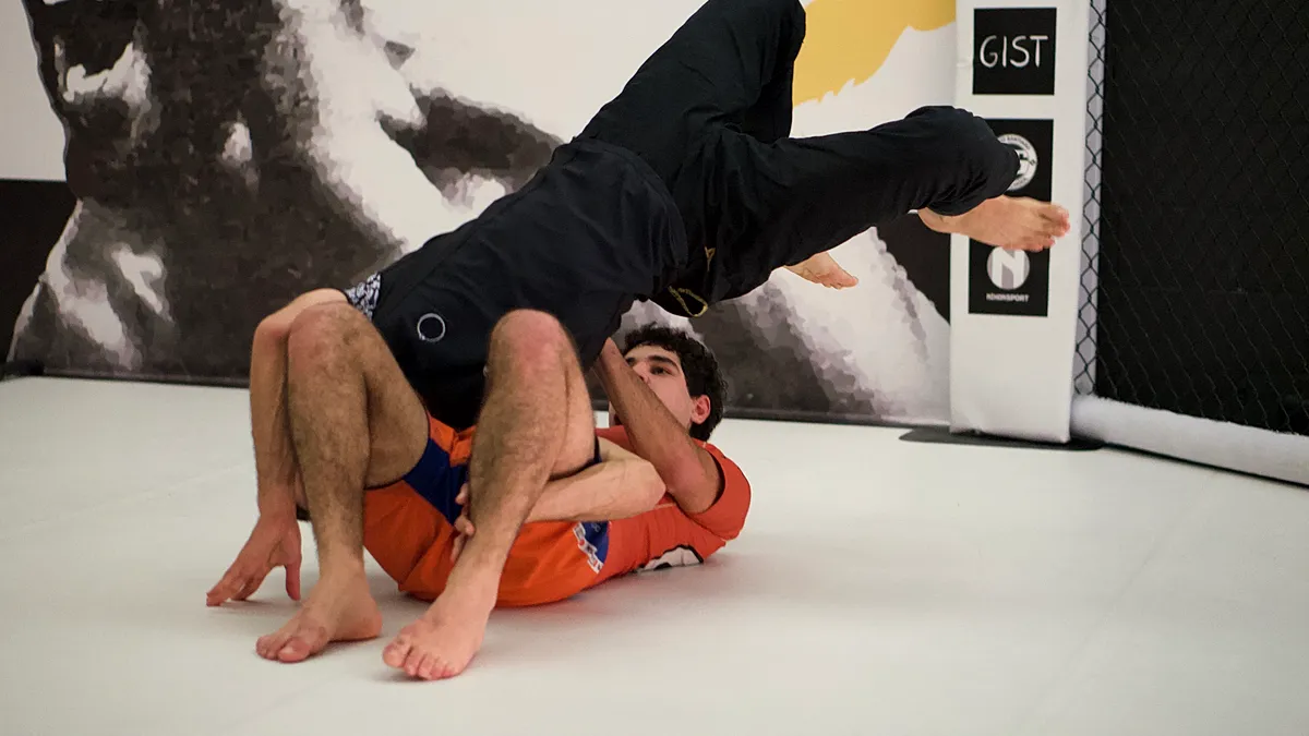 Een BJJ-beoefenaar demonstreert een grondpositie in de guard tijdens training.
