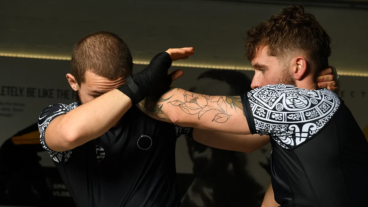 Twee BJJ-beoefenaars oefenen een clinch-positie met controletechnieken tijdens een sparringsessie.
